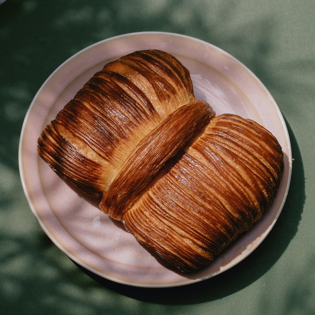 A laminated croissant on a pink plate
